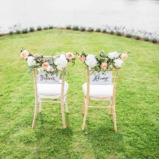 bride and groom chairs with pink and white flowers overlooking the ocean