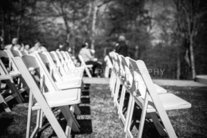 Side View of Ceremony Guests Sitting Down in White Chairs