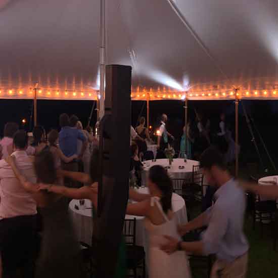 conga line at maine wedding under tent with white uplights